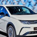 Carro elétrico BYD Dolphin Mini 2026 em movimento sobre uma ponte, ilustrando benefícios como isenção ou redução do IPVA de carro elétrico no Brasil.