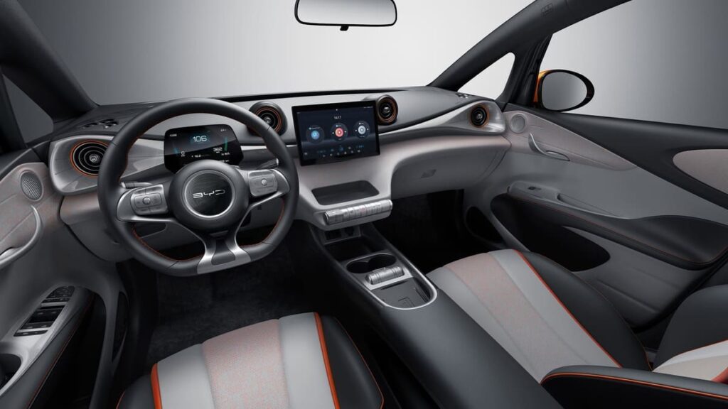 Interior moderno do BYD Dolphin Mini com painel digital, volante multifuncional e central multimídia em destaque.