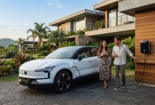 Fotografia de um SUV elétrico Volvo EX30 branco estacionado na rampa de uma casa moderna de alto padrão enquanto carrega em um carregador de parede (wallbox). Ao lado do carro, um casal sorri e conversa, ilustrando a rotina de quem aproveita as vantagens do IPVA Carro Elétrico MG.